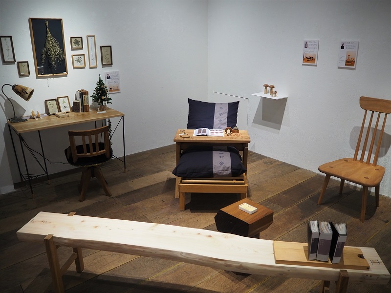 木製のベンチ、椅子、机、小物が並ぶギャラリー展示室、温かみのあるニュートラルな色調